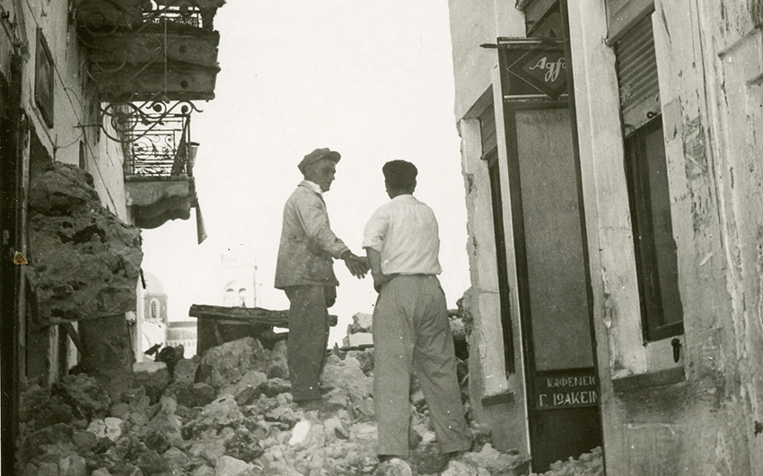 Two men standing on a pile of rubble in Fira after the July 1956 earthquake in Santorini.